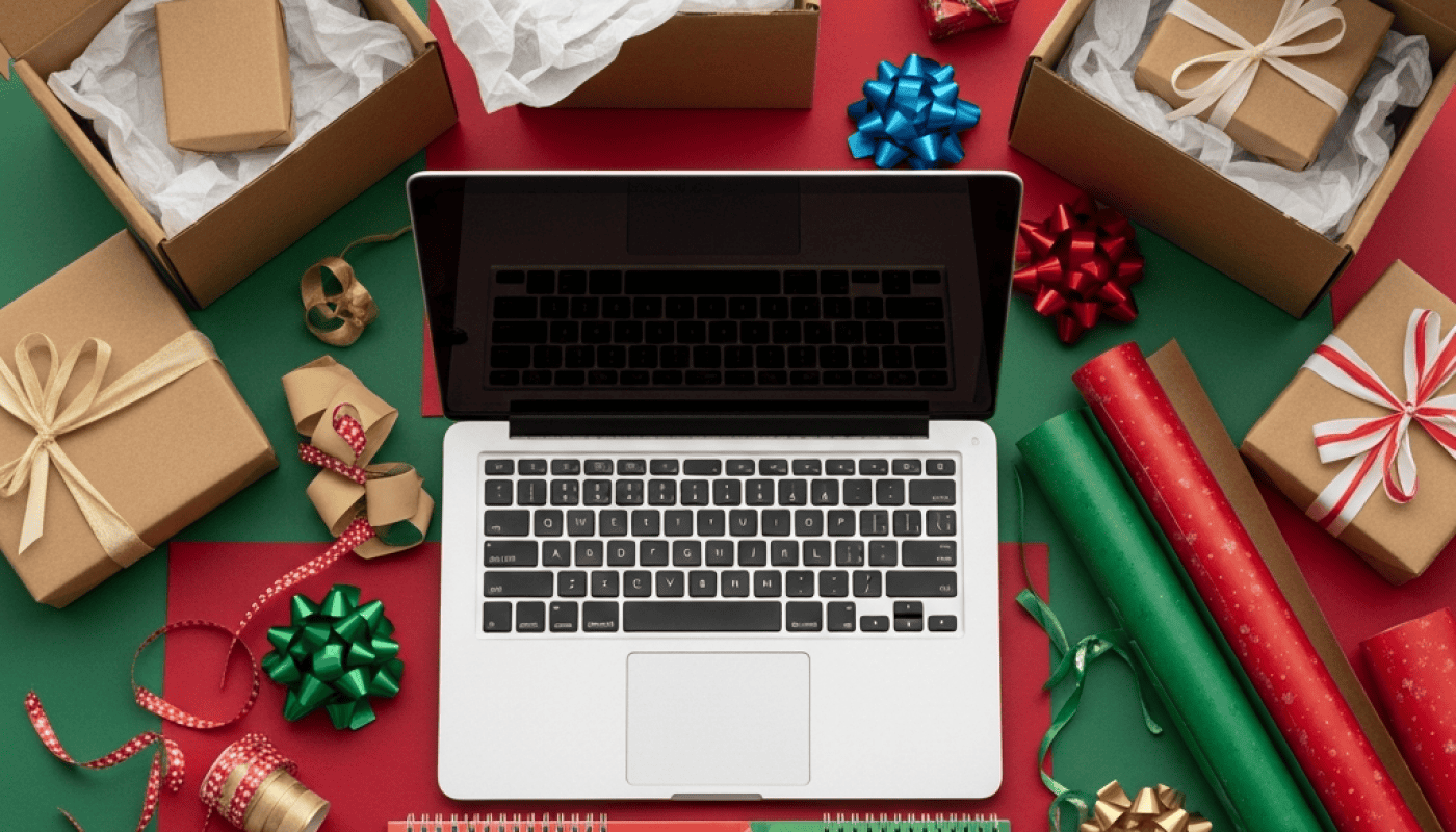 Festive gift wrapping scene with laptop, presents, and holiday decorations.